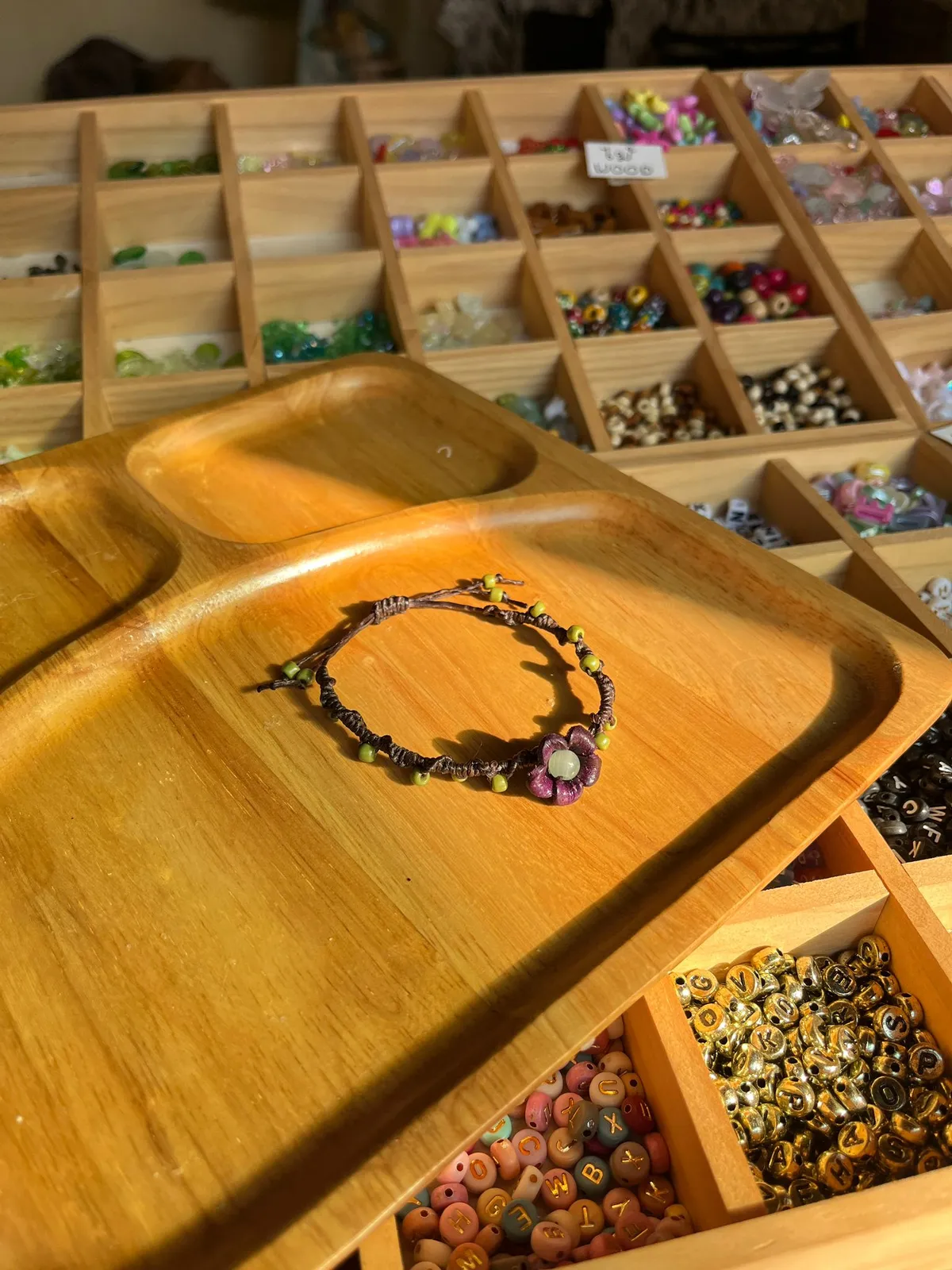 Handmade bead bracelet on a wooden tray with bead compartments.