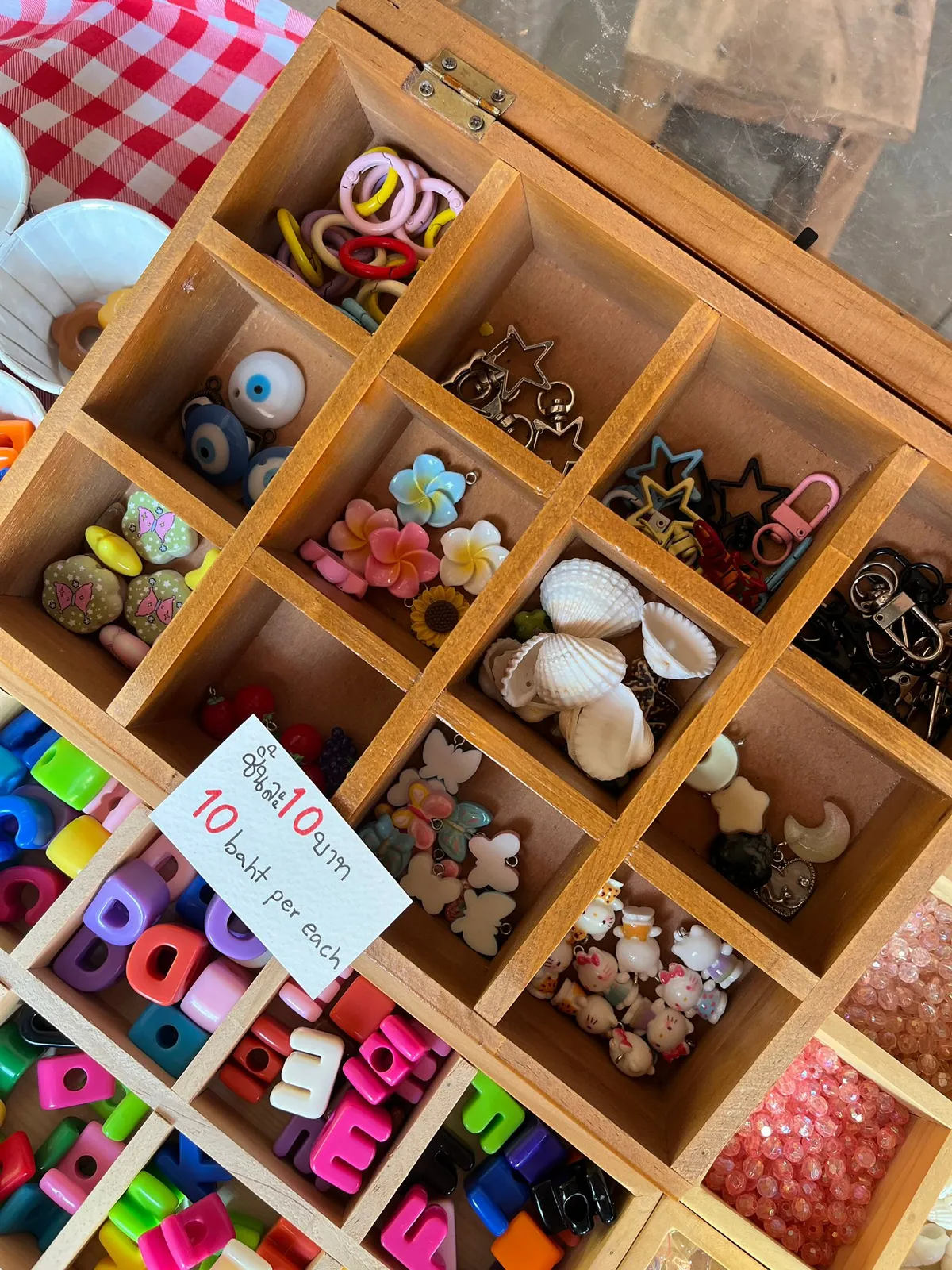 Wooden organizer with colorful beads and charms for jewelry making.