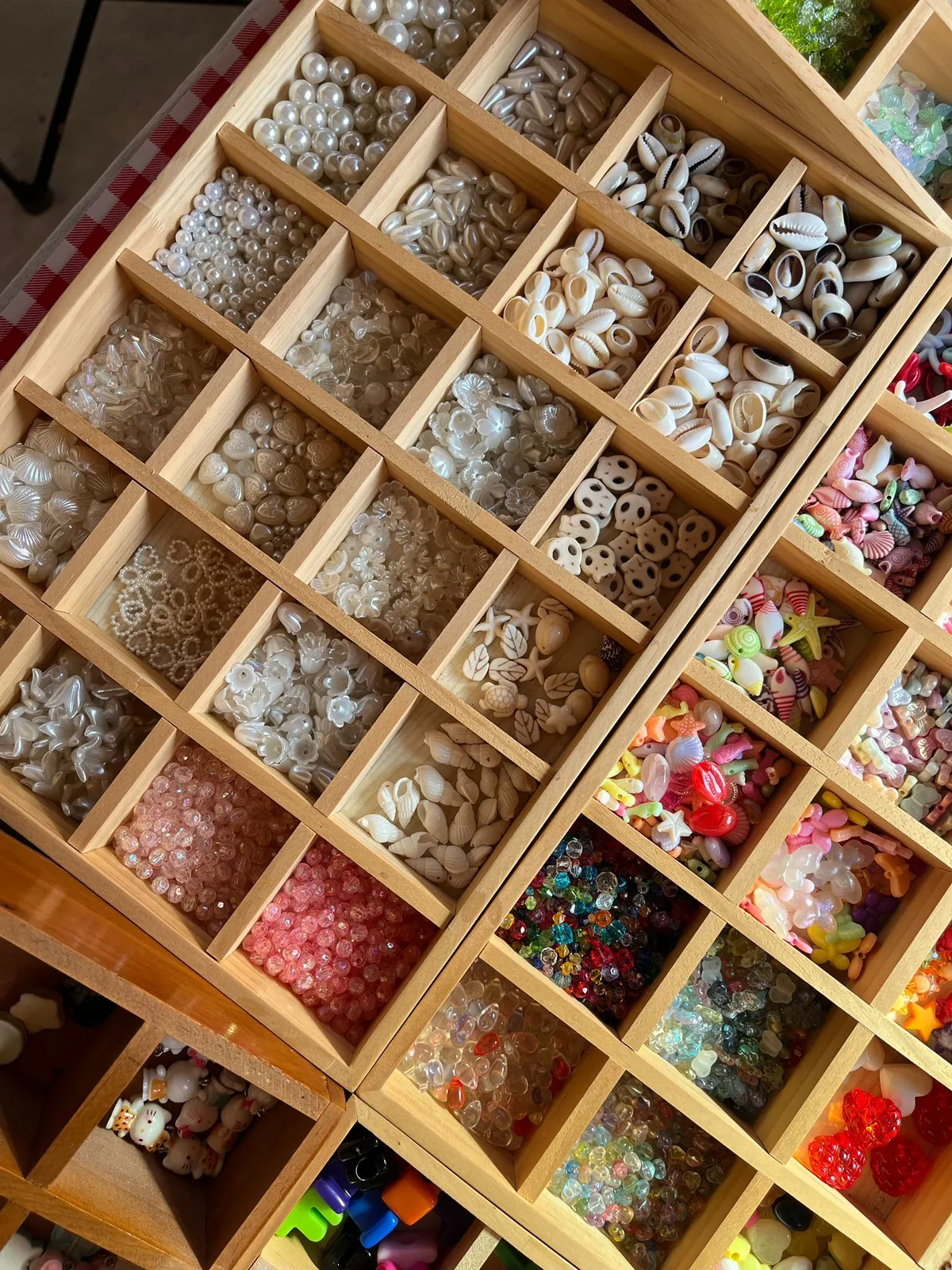 Wooden organizer with assorted colorful beads and shells.