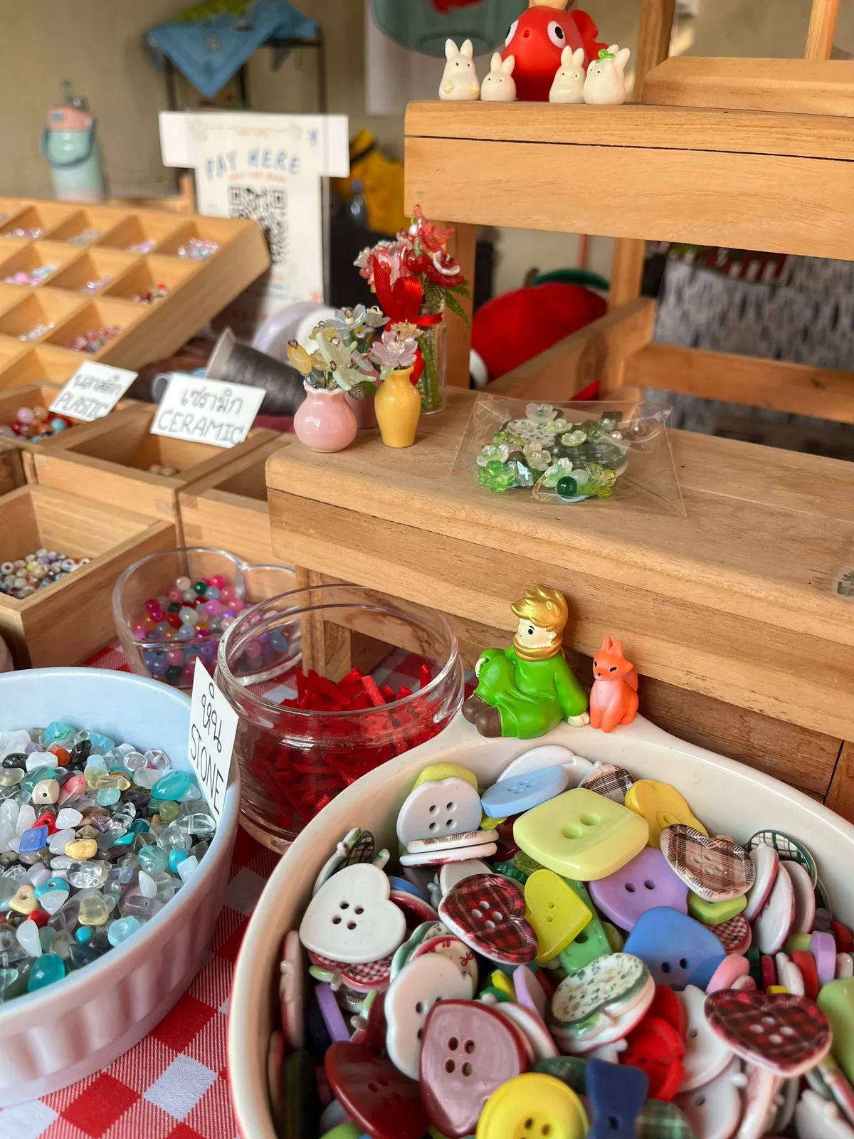 Colorful craft supplies with buttons and beads on a wooden shelf.