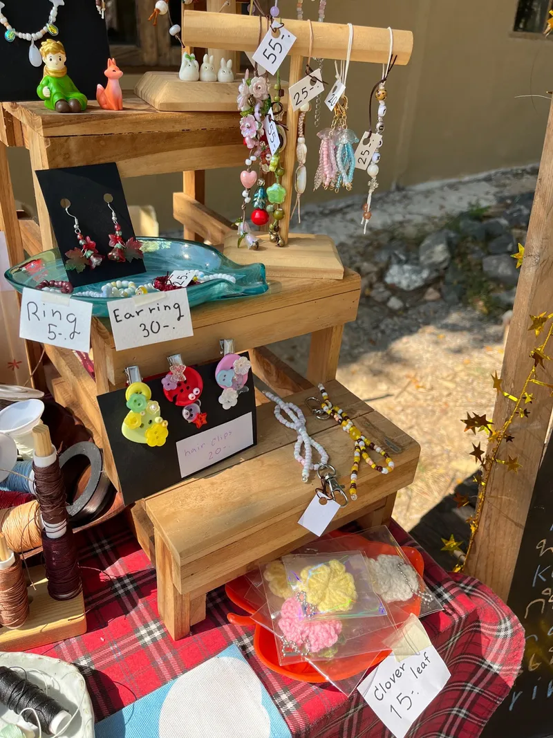 Outdoor display of handmade bead jewelry on a wooden stand.