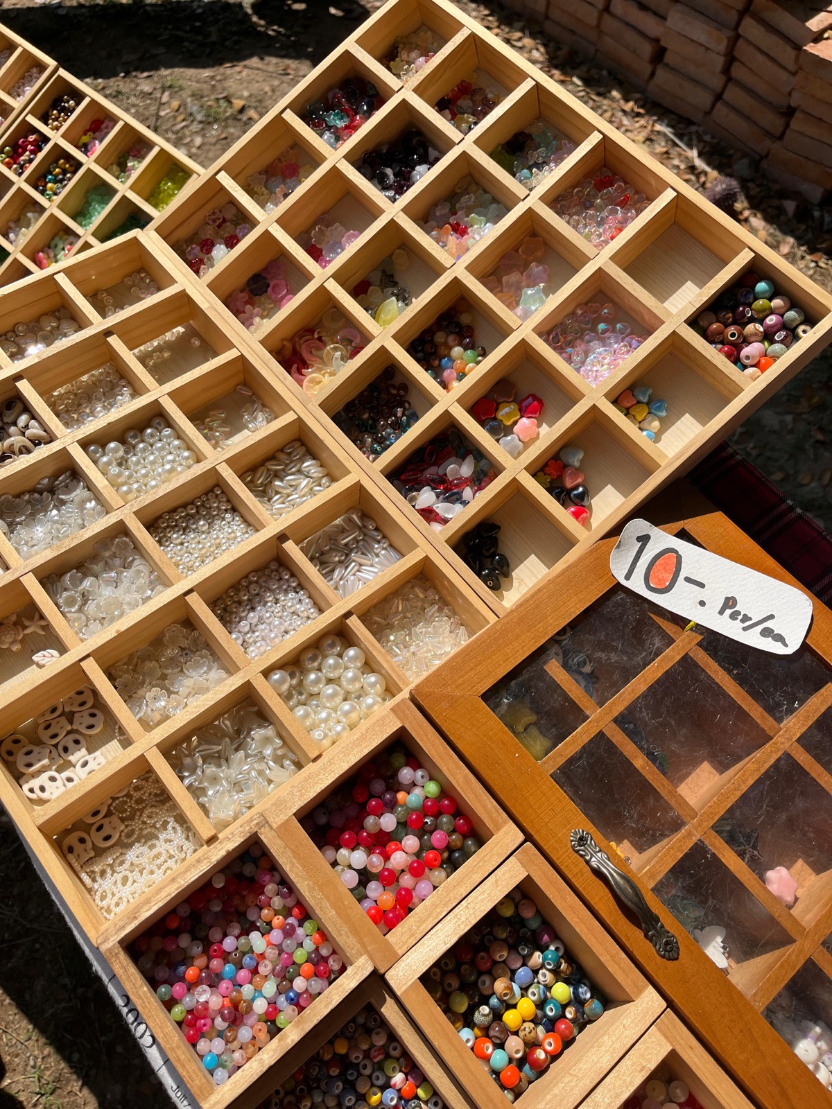 Colorful beads arranged in wooden compartments at a craft workshop